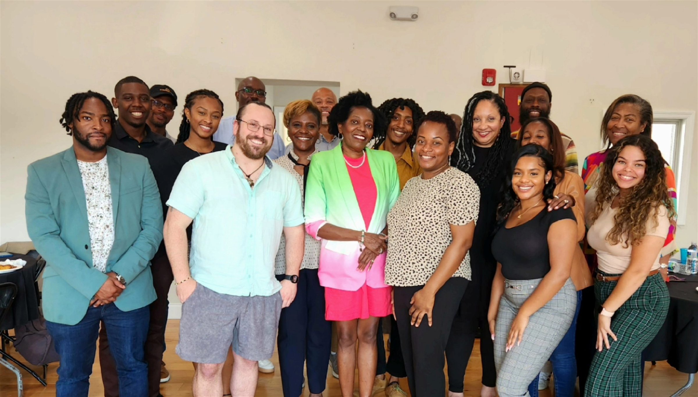 A group of about 20 Black journalists, media makers, and artists from South Jersey (plus a white guy named Joe in the front row) smile as they pose for a photo after a local journalism event.